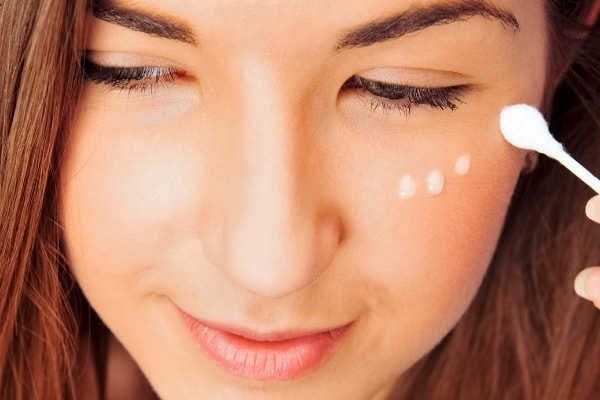 woman putting on eye cream 