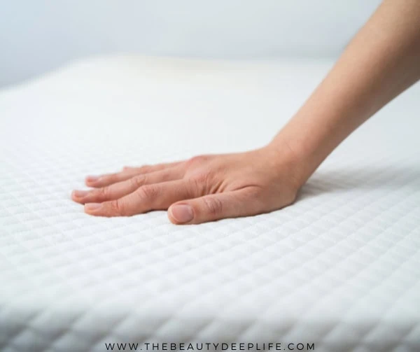 woman's hand touching a mattress