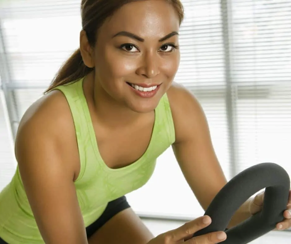 woman on bike exercising with glowing skin