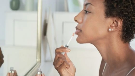 Woman applying lipstick for her self-care makeup routine.