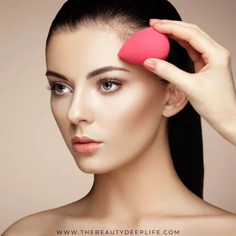 woman applying foundation makeup with a sponge