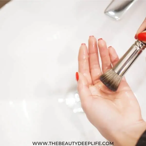 woman washing makeup brush in the sink