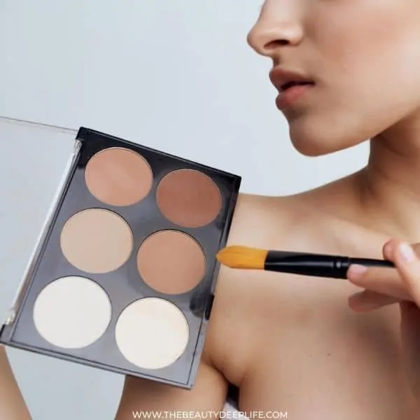 woman holding contouring makeup powder and a makeup brush