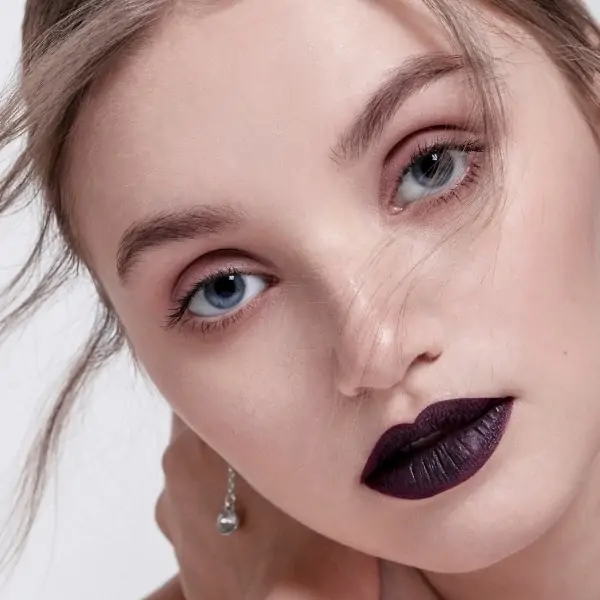 young girl with a fall makeup look that features very dark lipstick