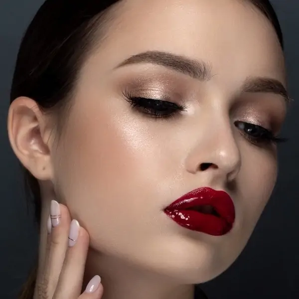 woman with  a classic fall makeup look that has dark red lip gloss and champagne eyeshadow