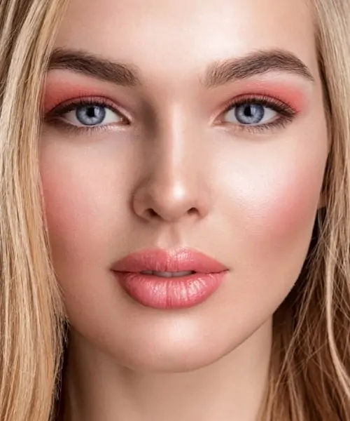 woman with blue eyes and a coral eyeshadow look