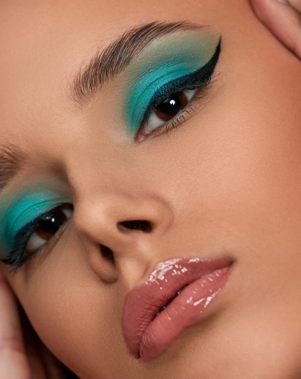 woman with blue-green colorful eye makeup look for her brown eyes