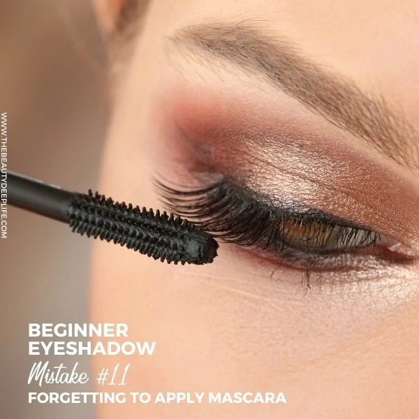 young woman applying mascara with text overlay beginner eyeshadow mistake 11 forgetting to apply mascara