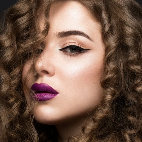 woman with a fall makeup look that has bold purple lipstick