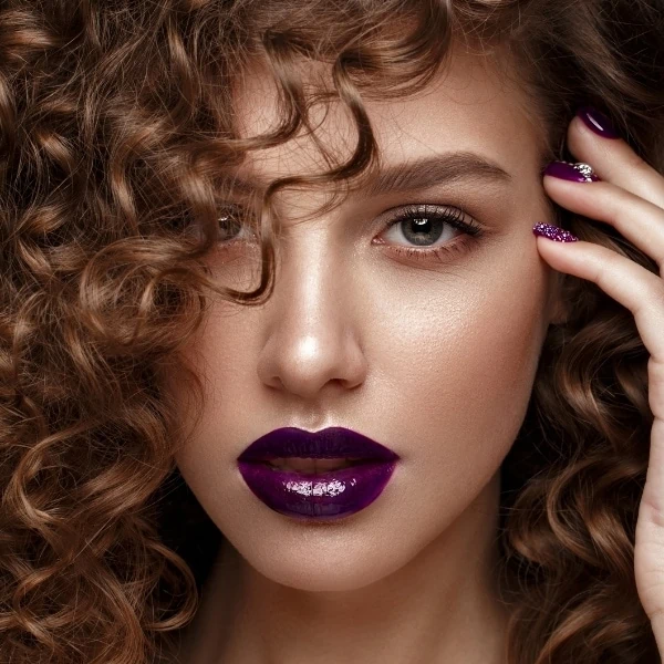 woman with a fall makeup look featuring dark purple glossy lipstick