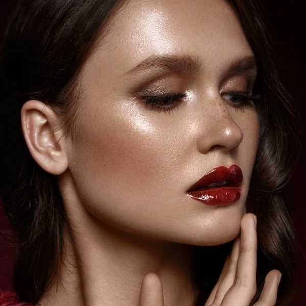 woman with a fall makeup look featuring dark red glossy lips and glowy skin