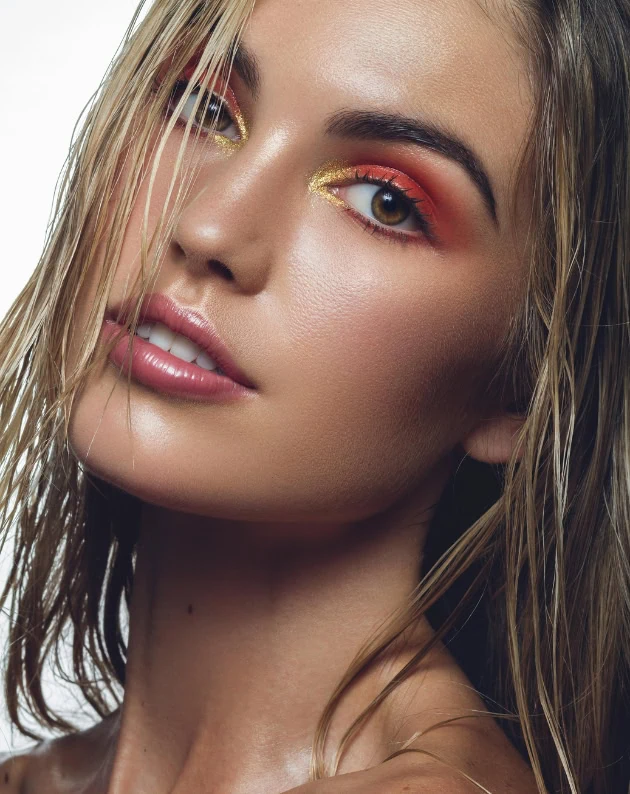 woman with a bright orange-red with gold eye makeup look for summer