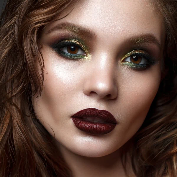 woman with a fall makeup look featuring green smokey eyes and a bold lip