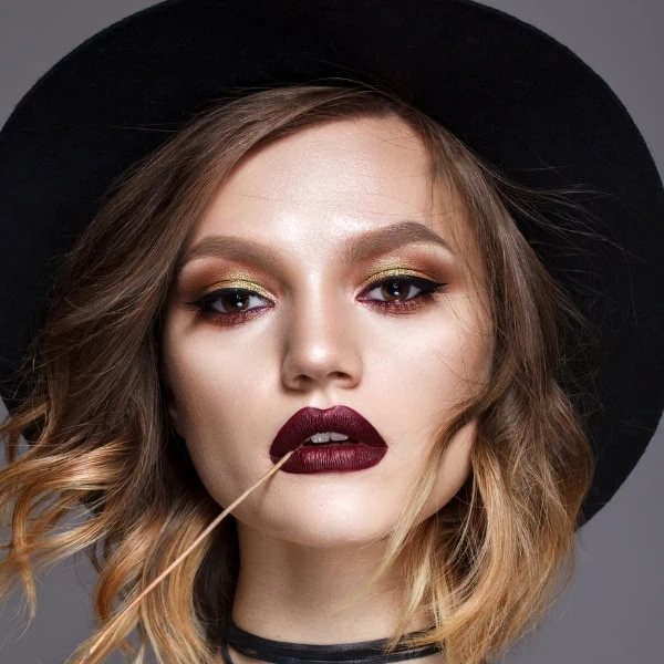 woman with a fall makeup look using gold, rust and brown eyeshadows with a wine colored lip