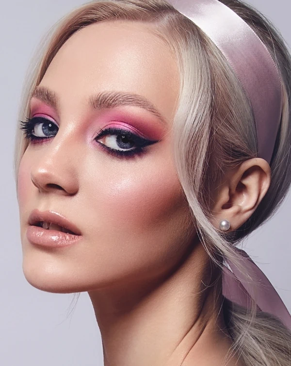 woman with blue eyes and a pink eyeshadow makeup look with a cat-eye liner