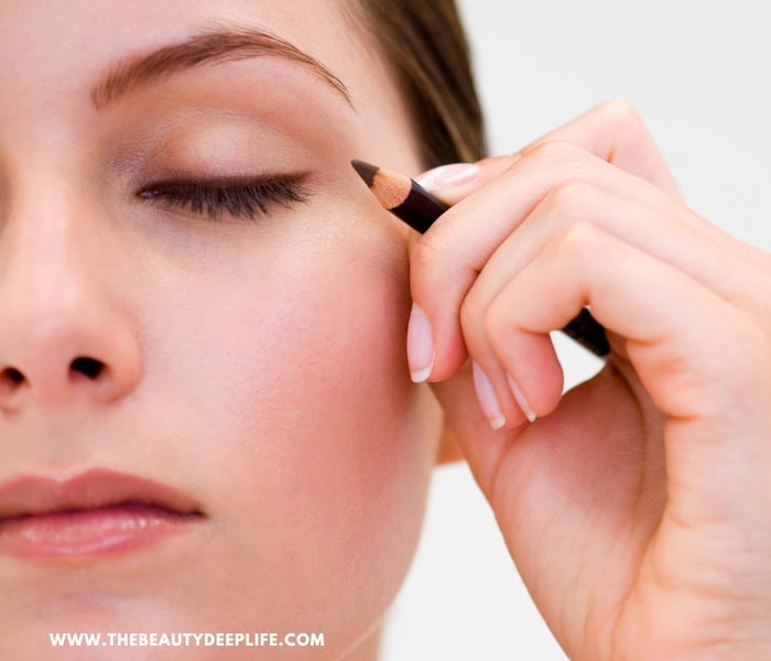 woman applying liner pencil to her eye