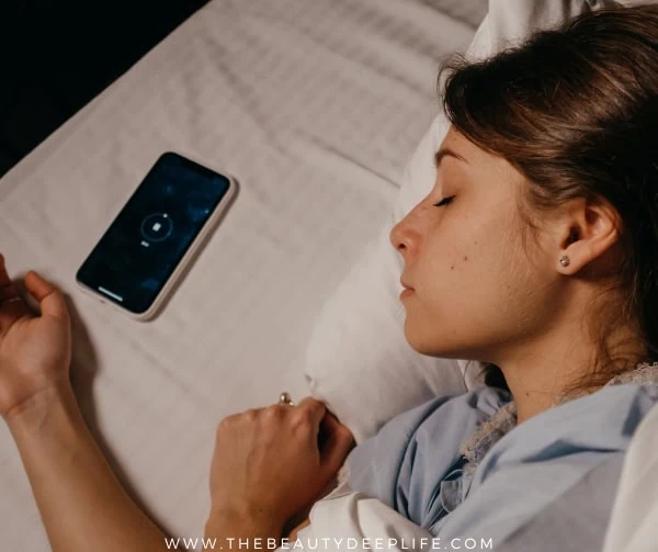 woman sleeping next to phone with music playing