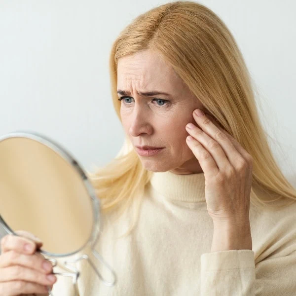 woman looking at her face in the mirror