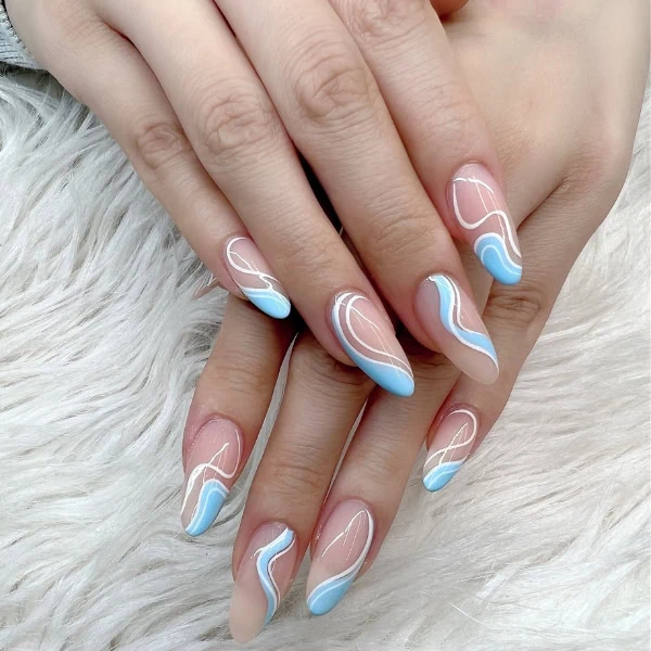 female hands with blue and white swirl nail design