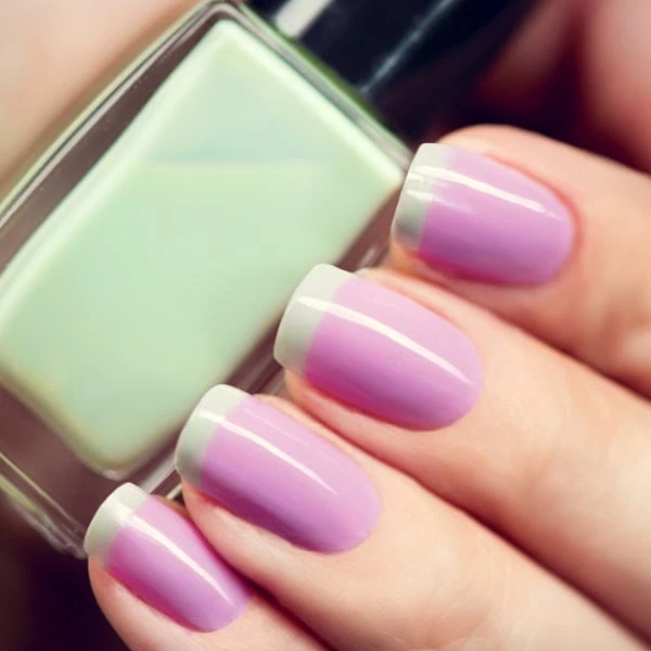 female hand with pastel purple with green tip nails