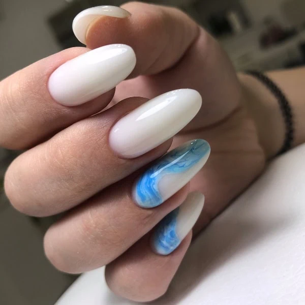 female hand with white and blue marble ocean themed nail design