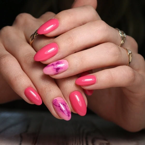 female hands with bright pink and marble nails manicure trend