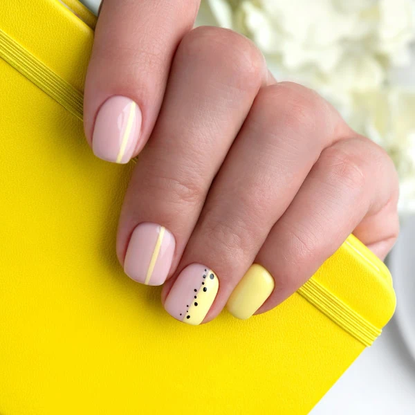 female hand with yellow pastel minimalist nails