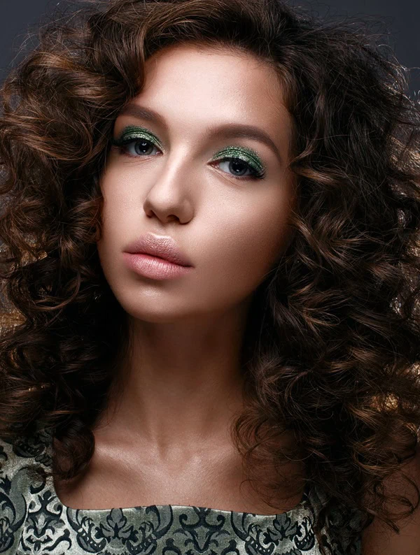 woman with an example of an easy christmas makeup looks wearing green sparkle eye makeup and subtle face