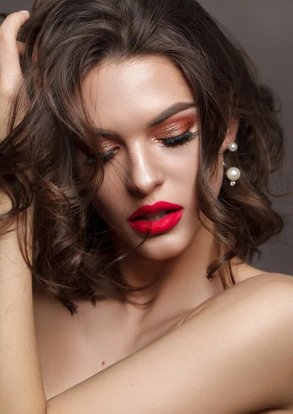 brunette woman with bright red lips and gold and red eyeshadow for her valentine's day makeup idea