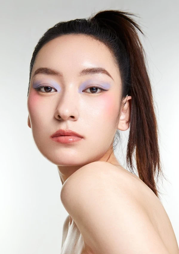 beautiful young asian woman with fashionable spring makeup using pastel purple eyeshadow