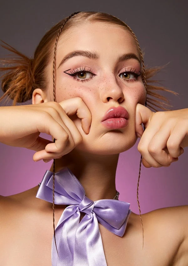 young girl with spring makeup look using pink eyeshadow and graphic eyeliner