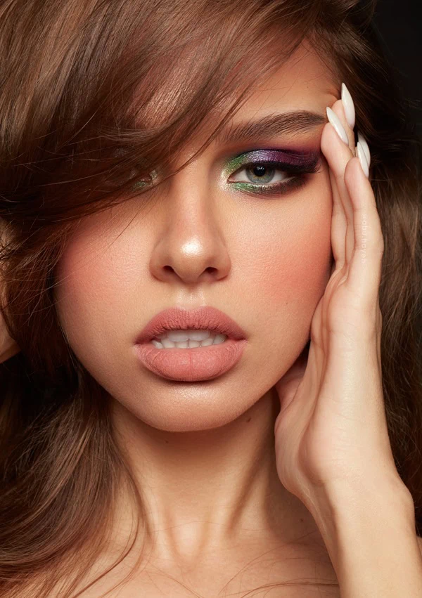 woman with colorful green and purple eye makeup