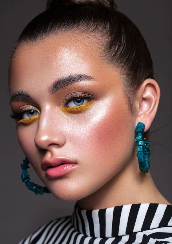 woman with blue eyes and colorful yellow under eye makeup