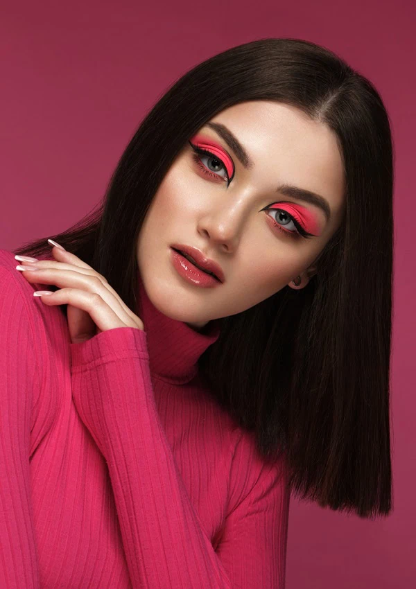 woman with colorful pink eyeshadow makeup and graphic eyeliner