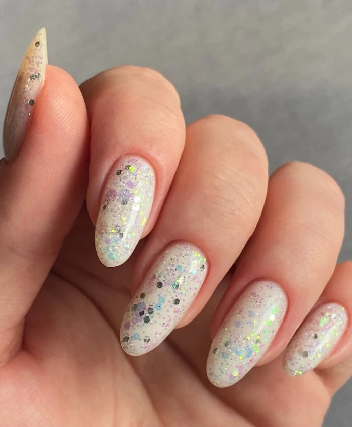 woman's hand with milky white nails and glitter for spring