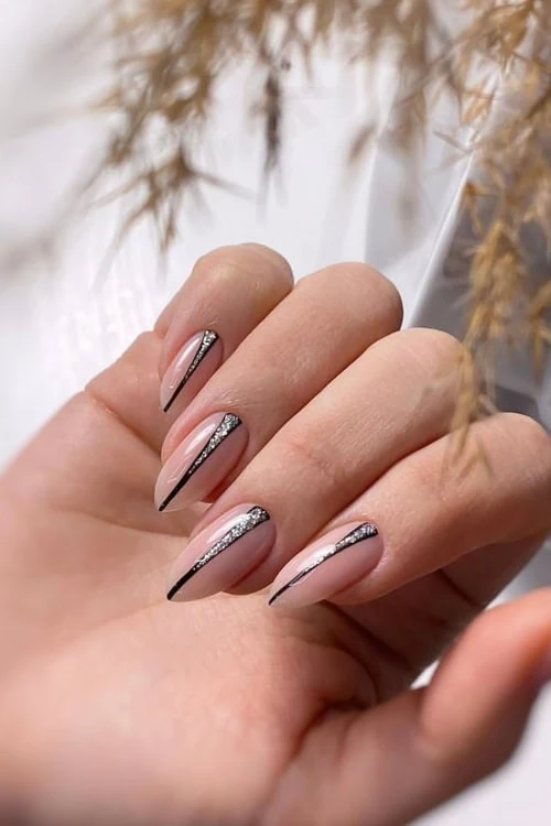 female hand with a elegant manicure featuring silver glitter and a black stripe down the middle