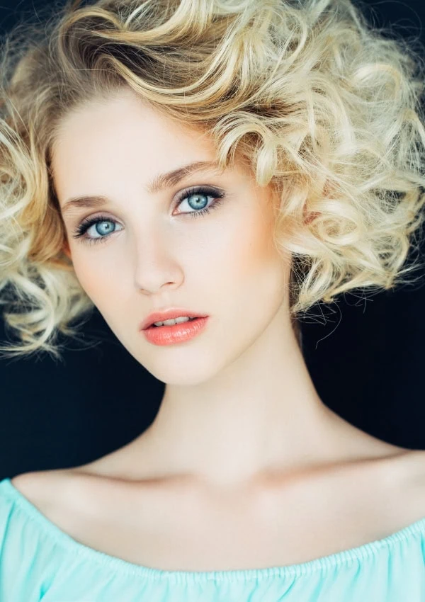 woman with curly bob length platinum blonde hair