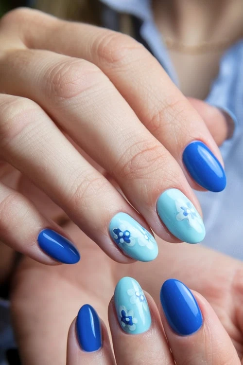 hand with light and vibrant blue nails with flowers