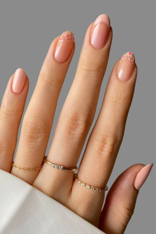 femals hand with a simple nail idea featuring peachy tones and flowers