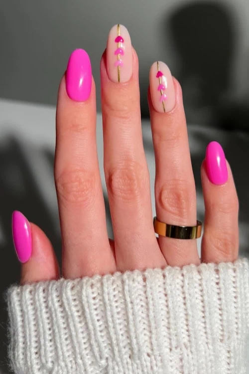 female hand with simple pink nail idea with hearts design