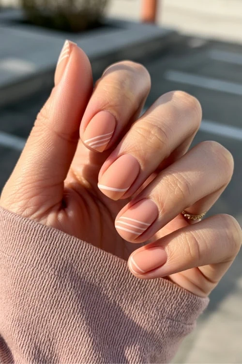 hand with matte peach nails with a  minimalist geometric design