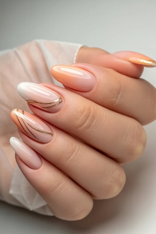 hand with ombre nails peach and gold metallic accents