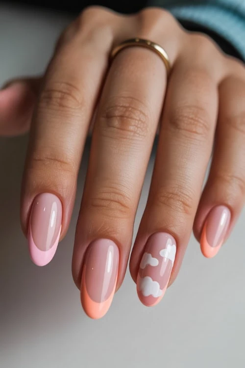 hand with pink and peach french tips with white clouds nail art