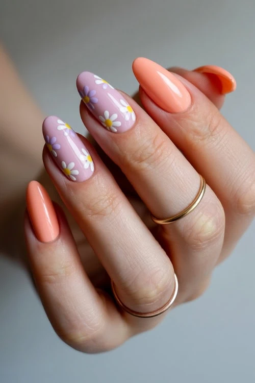 hand with peach and purple pastel nails with floral nail art