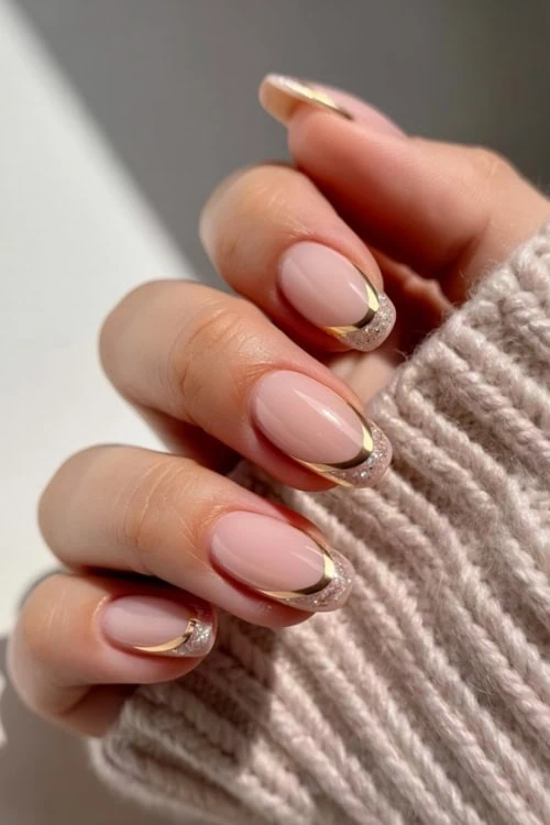 hand with gold and glitter french tip nails