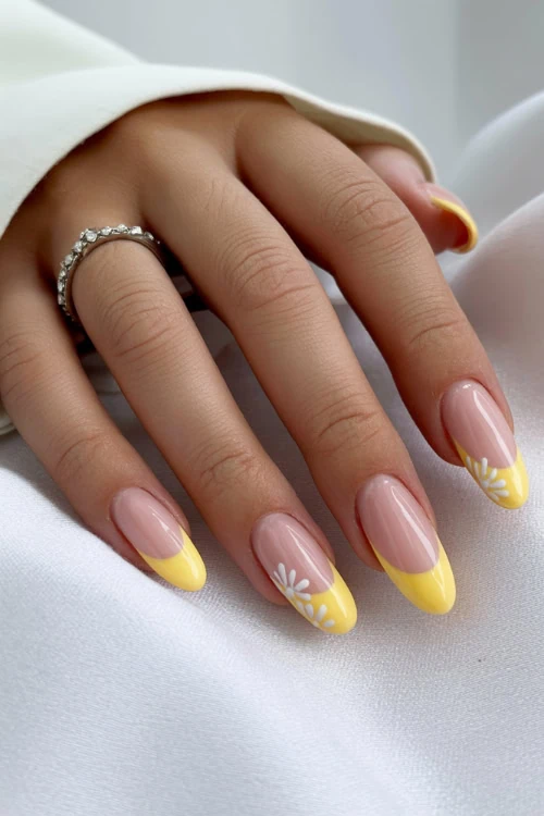 hand with yellow french tip nails with white flowers