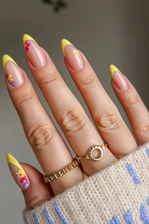 hand with yellow french tips and flower nail art design