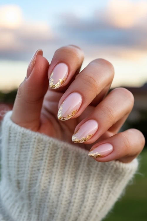 hand with almond nails and gold accents