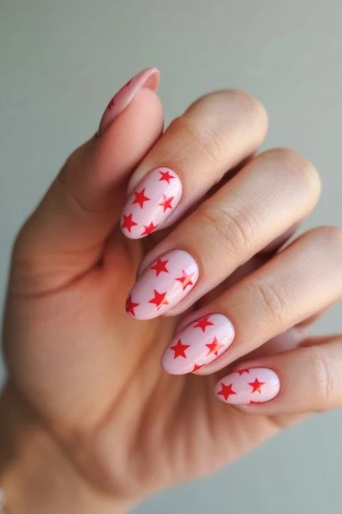 hand with short pink almond nails with red stars