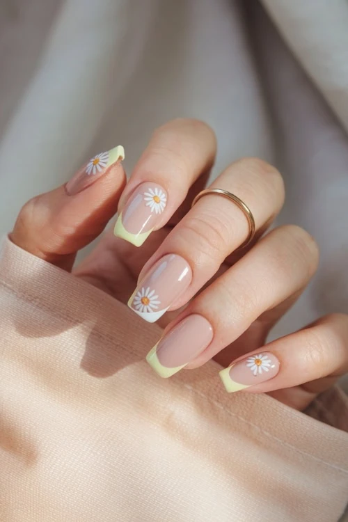 female hand with yellow french tips and daisy nail design